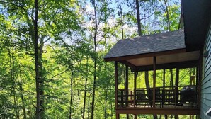 Eine Holzterrasse mit Sitzgelegenheiten, umgeben von Waldgebiet.