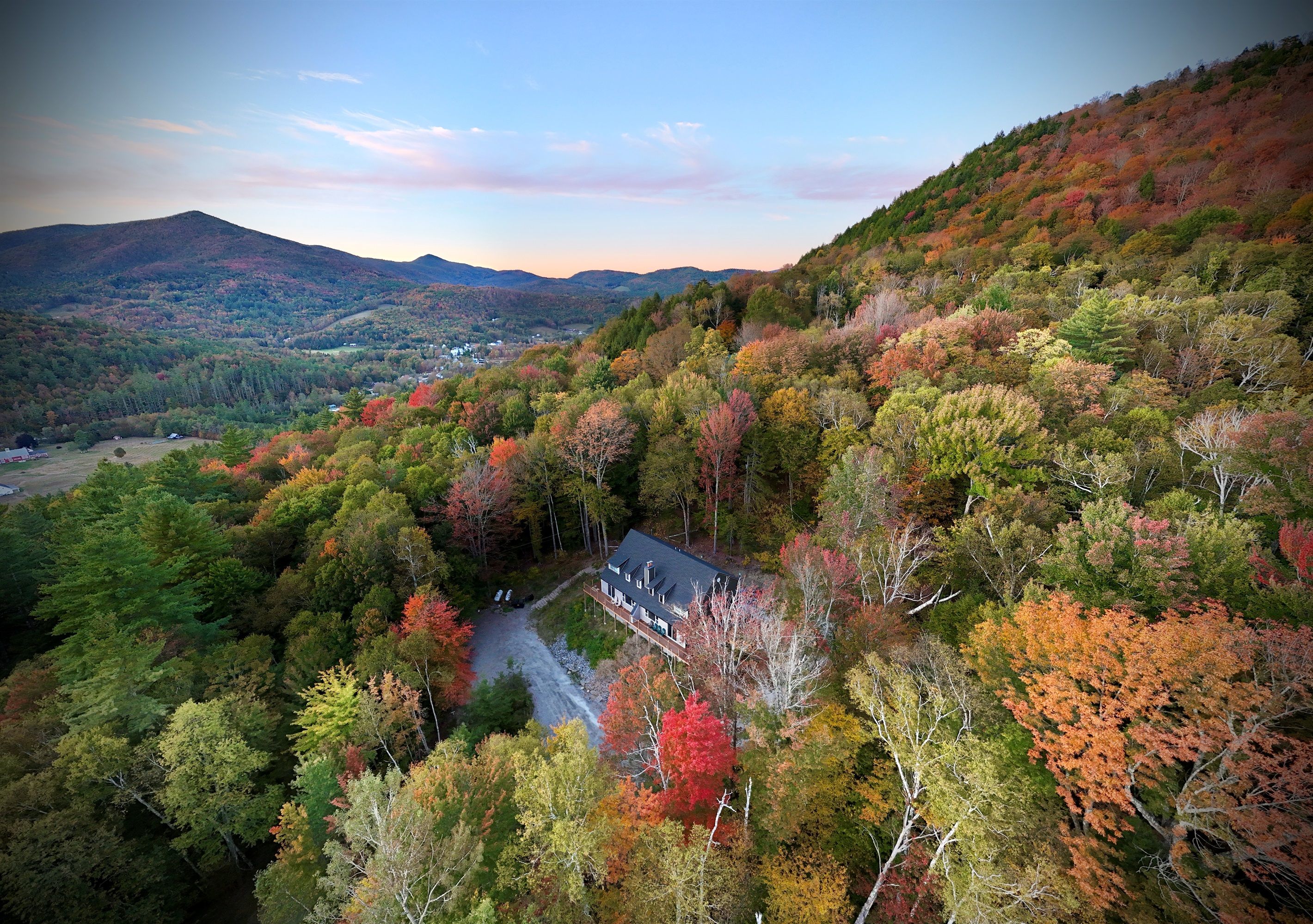 A house surrounded by autumn foliage with a view of distant mountains.