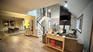 Ein geräumiger Wohnbereich mit Holzboden, einer Treppe, einem Esstisch mit Stühlen und einem Sofa.