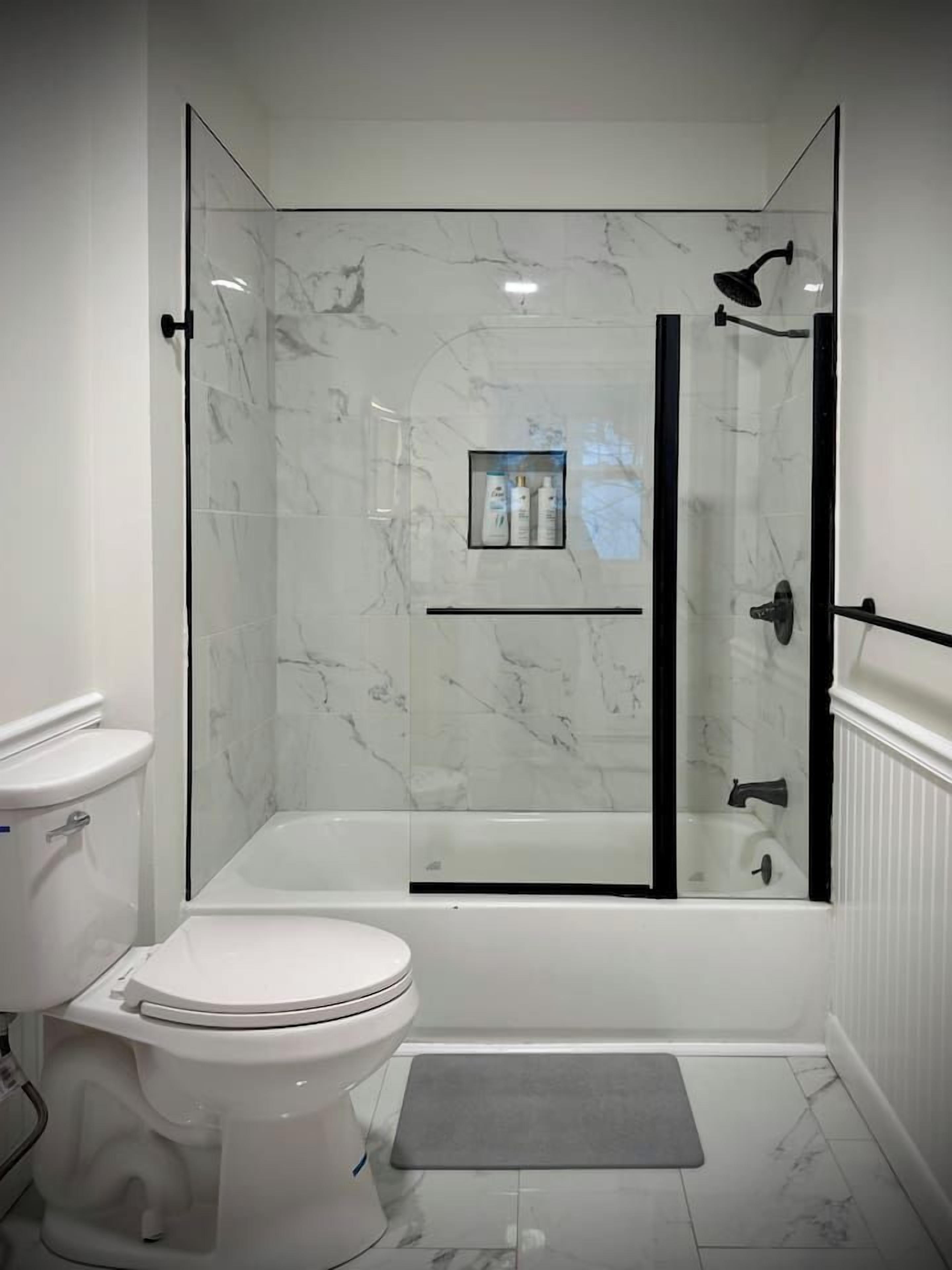 A modern bathroom with a glass-enclosed shower, a toilet, and a vanity with a mirror.