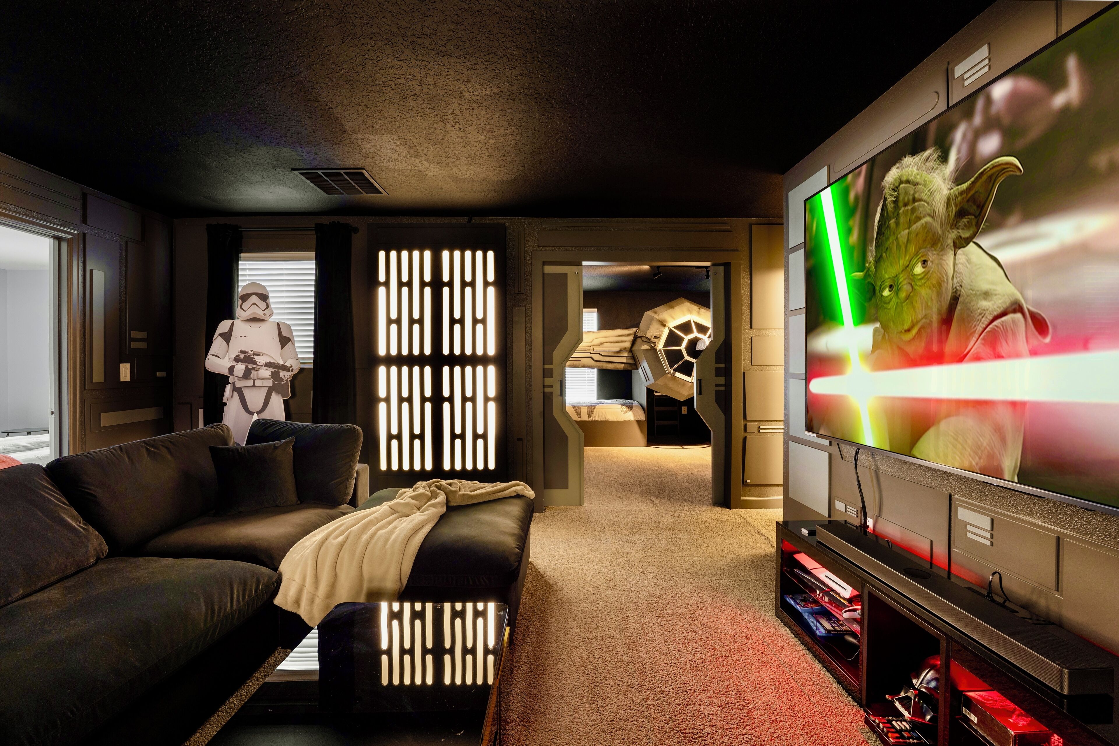Un salon moderne doté d’un grand téléviseur à écran plat, d’un canapé en cuir et d’une décoration sur le thème de Star Wars.
