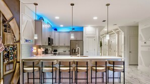 Una cocina moderna con una isla central, taburetes de bar e iluminación colgante.