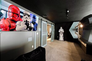 Una habitación con decoración temática de Star Wars, incluyendo un cartel grande de Stormtroopers, un TIE fighter a tamaño real y una figura de Stormtrooper.