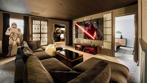 Una sala de estar moderna con un televisor de pantalla plana grande, un sofá y una figura con temática de Star Wars.