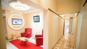 Un moderno vestíbulo de hotel con alfombra roja, una mesa de centro redonda y sillones rojos.