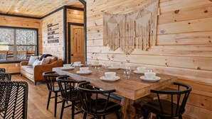 A wooden interior with a dining table set for six, a sofa, and a wall-mounted macrame decoration. - NEW, INDOOR POOL, GAME ROOM, BUNK ROOM, HOT TUB (Sevierville)