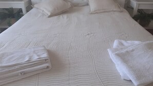Una cama bien hecha con un cabecero capitonado, dos almohadas y toallas dobladas sobre la cama.