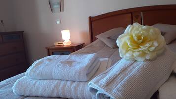 Una cama bien hecha con toallas dobladas y una flor grande sobre la almohada.