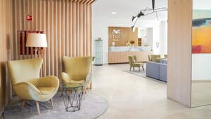 A modern lobby with a reception desk, two yellow armchairs, a glass coffee table, and a painting on the wall. - Vplaza Private Garage Balcony Pool View Flat (Portimão)
