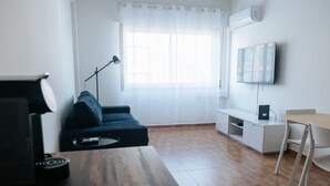 A modern living room with a sofa, a coffee table, a TV, and a desk. - Lisboa Almirante Reis Downtown Flat E (Lisbon)