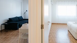 A room with a white bed, a white chair, a dark-colored sofa, and a small table with a lamp. - Lisboa Almirante Reis Downtown Flat E (Lisbon)