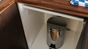A kitchen with a wooden countertop, a black induction cooktop, a white kettle, and a stainless steel trash bin. - Lisboa Almirante Reis Downtown Flat E (Lisbon)