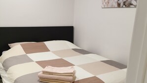 A neatly made bed with a checkered bedspread and folded towels.
