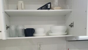 A kitchen with white cabinets, a marble countertop, a kettle, a toaster, and various dishes and utensils.