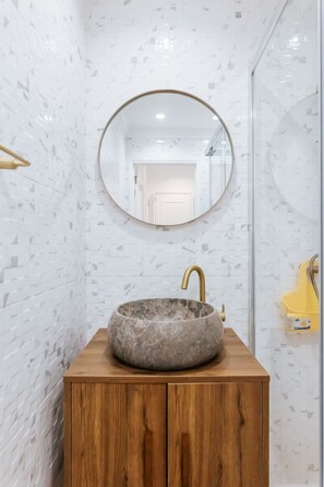 A bathroom with a round mirror, a stone sink, and a wooden vanity. - Lisboa Almirante Reis Central Flat D (Lisbon)