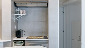 A modern kitchen with white cabinetry, a white countertop, and a wooden cutting board.
