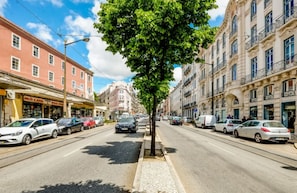 A street lined with parked cars and buildings, including a shop with a sign that reads "ADMICTION". - Downtown Lisbon Arroios Flat 3 (Lisbon)