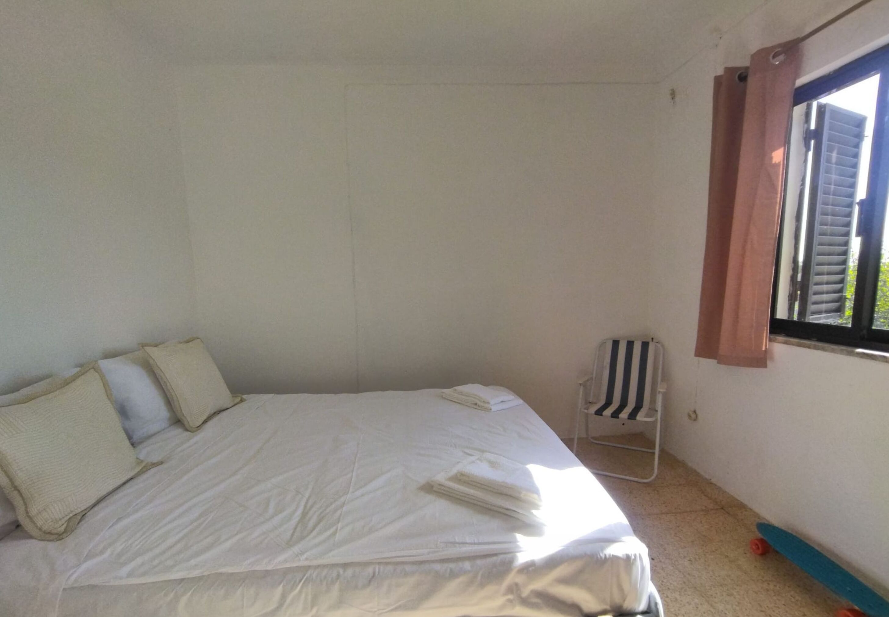 A simple room with a bed, a chair, and a window.
