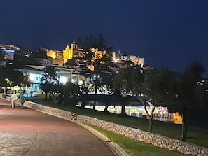 Um edifício histórico com uma torre imponente, cercado por um muro de pedra e árvores.