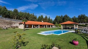 Una casa con piscina, terraza cubierta y pared de piedra.