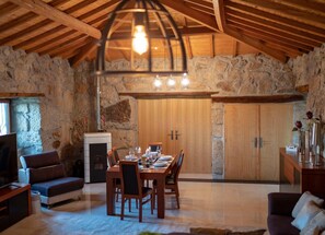 A cozy dining area with a stone wall, wooden ceiling beams, and a fireplace. - Luxury Villa Private Pool Belle Poque (Celorico de Basto)