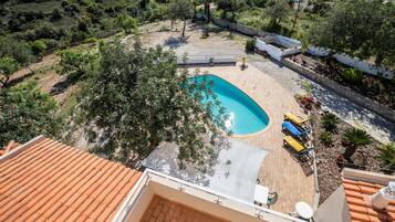 Relax in a backyard with a swimming pool and patio area, surrounded by lush vegetation.