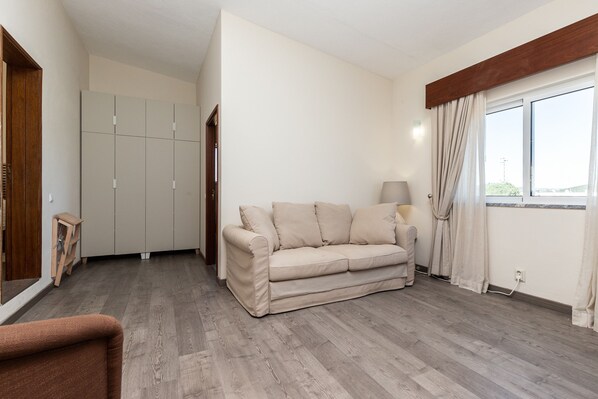 A room with a beige sofa, wooden flooring, a wooden wardrobe, and a window with curtains. - Looking to Landscape Sea View Private Pool Villa (Loulé)