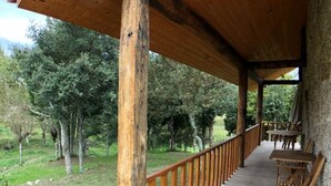 A wooden deck with a railing, surrounded by trees and a grassy area. - Vila Espigueiro I in Bustelo (Penafiel)