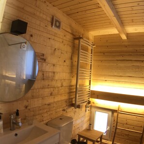 Ein Badezimmer in einer Holzhütte mit Waschbecken, Toilette und Spiegel.