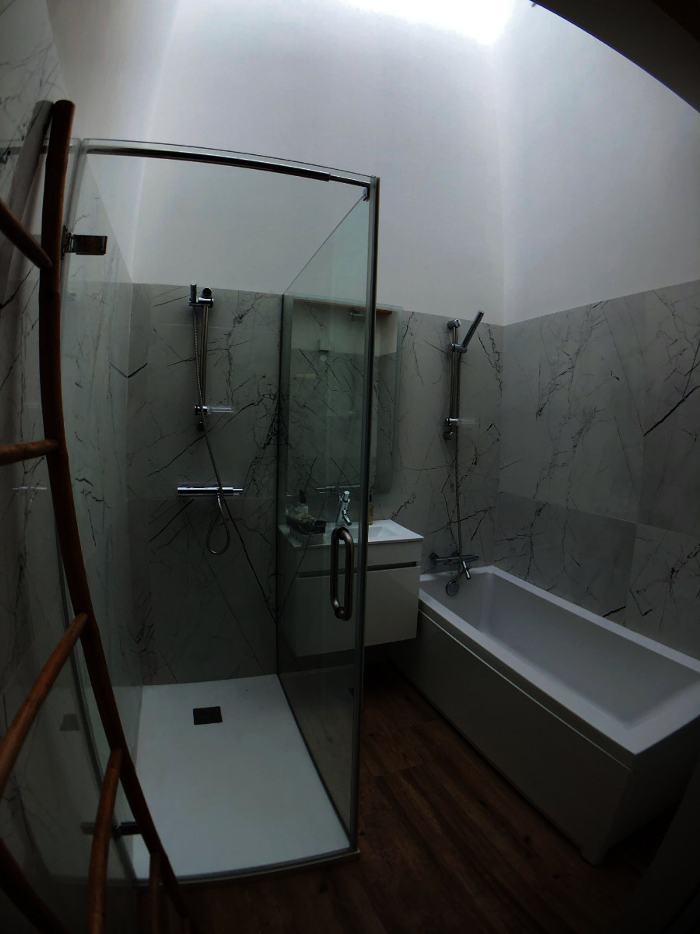 Een moderne badkamer met een douche met glazen wand, een wit wastafelmeubel en een bad.