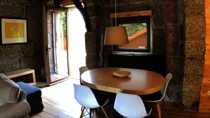 A rustic dining area with a round wooden table, four chairs, and a hanging lamp. - Vila Forno in Bustelo (Penafiel)