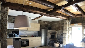 A rustic kitchen with stone walls, wooden beams, and modern appliances. - Vila Forno in Bustelo (Penafiel)