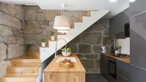 A modern kitchen with a wooden island, stone walls, and a staircase. - Vila Beiral in Penafiel (Penafiel)