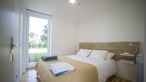 Ein Schlafzimmer mit Bett, Nachttisch, Fenster und Tür.