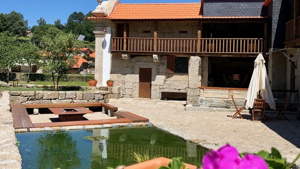 Ein Innenhof mit Pool, Steinbauten und einer Holzterrasse.
