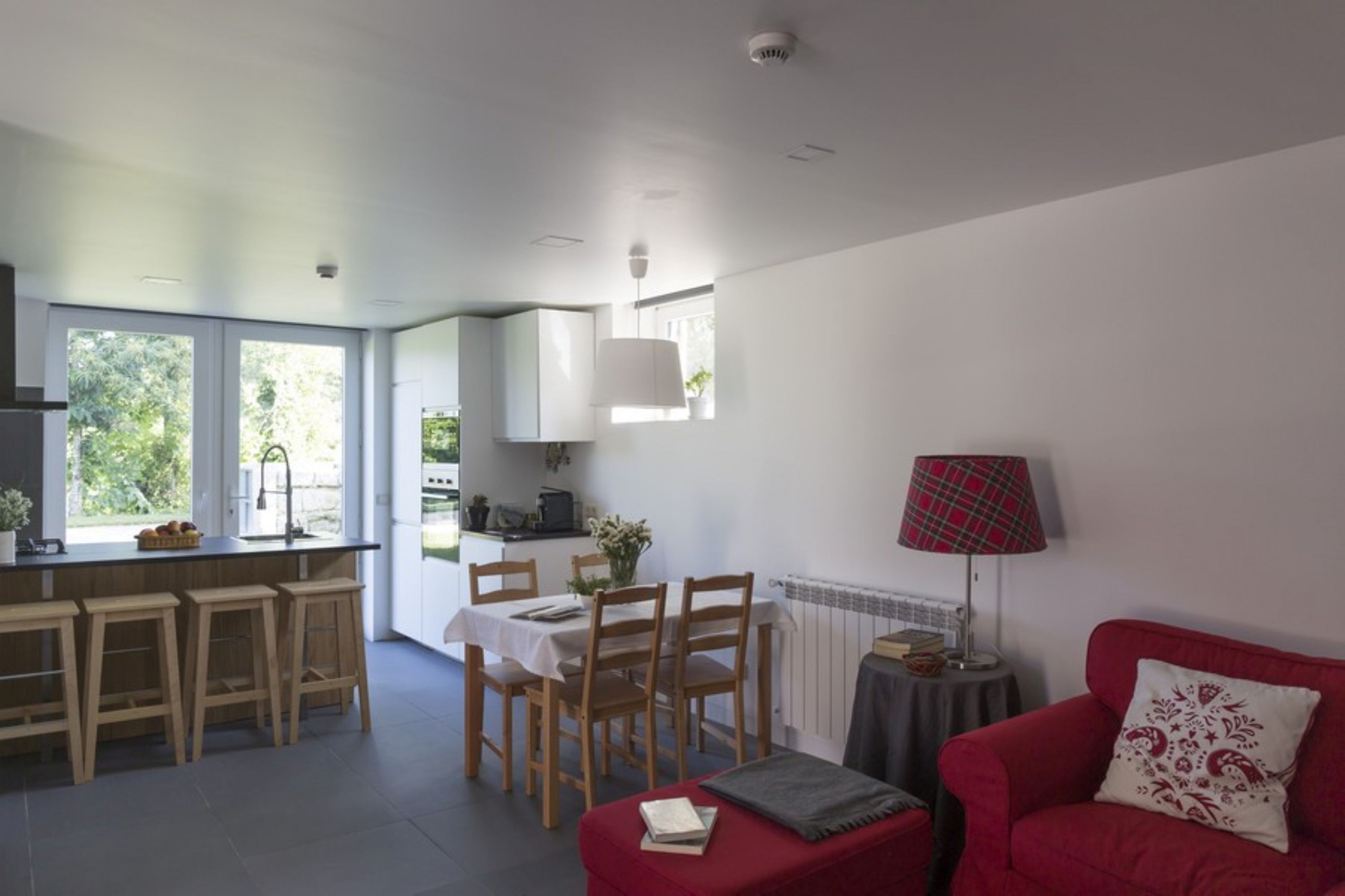 Una cocina moderna con comedor, un sofá rojo y una lámpara.