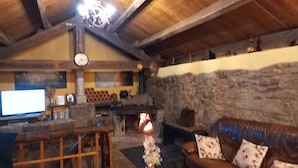 A cozy room with a stone wall, a fireplace, a wooden ceiling, and a leather sofa. - New Riyork Sweet Home (Montalegre)