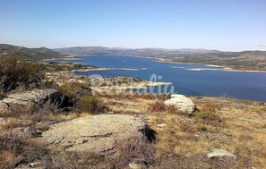 Un paisaje costero con una extensa masa de agua, terreno rocoso y vegetación escasa.