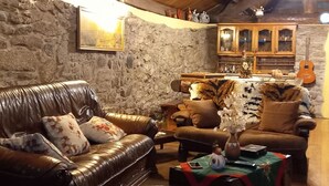 A cozy loft-style living room with exposed wooden beams, stone walls, and leather furniture. - New Riyork Sweet Home (Montalegre)