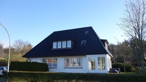 A two-story house with a dark roof, white exterior walls, and multiple windows.