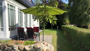A patio with outdoor furniture, a stone wall, and a hedge.