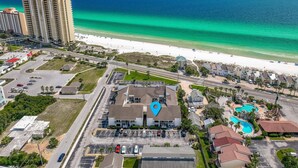 Vista aérea de una zona costera con un hotel, una playa y un estacionamiento.