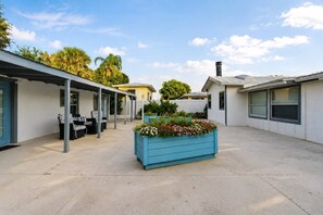 A covered outdoor area with a seating arrangement and a planter with flowers.