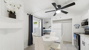 A modern kitchen with white cabinets, a round dining table, and a ceiling fan. - Guesthouse by the Beach (Fort Pierce)