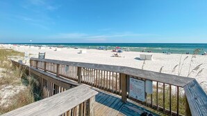 A beach with a wooden boardwalk leading to the shore, clear skies, and a sign indicating beach rules. - Seaside Beach & Racquet Club 3301 – Beachfront w Pool! 🌊☀️ (Orange Beach)
