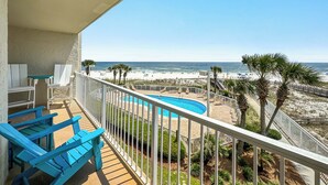 A balcony with blue chairs, a pool, and a view of the beach and ocean. - Seaside Beach & Racquet Club 3301 – Beachfront w Pool! 🌊☀️ (Orange Beach)