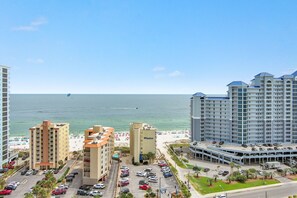 A coastal hotel with multiple buildings, a parking lot, and a beach in the background. - RELAX AT THE  BEACH IN THIS GORGEOUS GULF FRONT CONDO! (Gulf Shores)