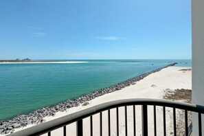 A coastal view with a sandy beach, calm sea, and a rocky breakwater. - BEACHFRONT, FAMILY FRIENDLY, LOW FLOOR, INDOOR/OUTDOOR POOL | BEACHBALL PROPERTIES (Orange Beach)