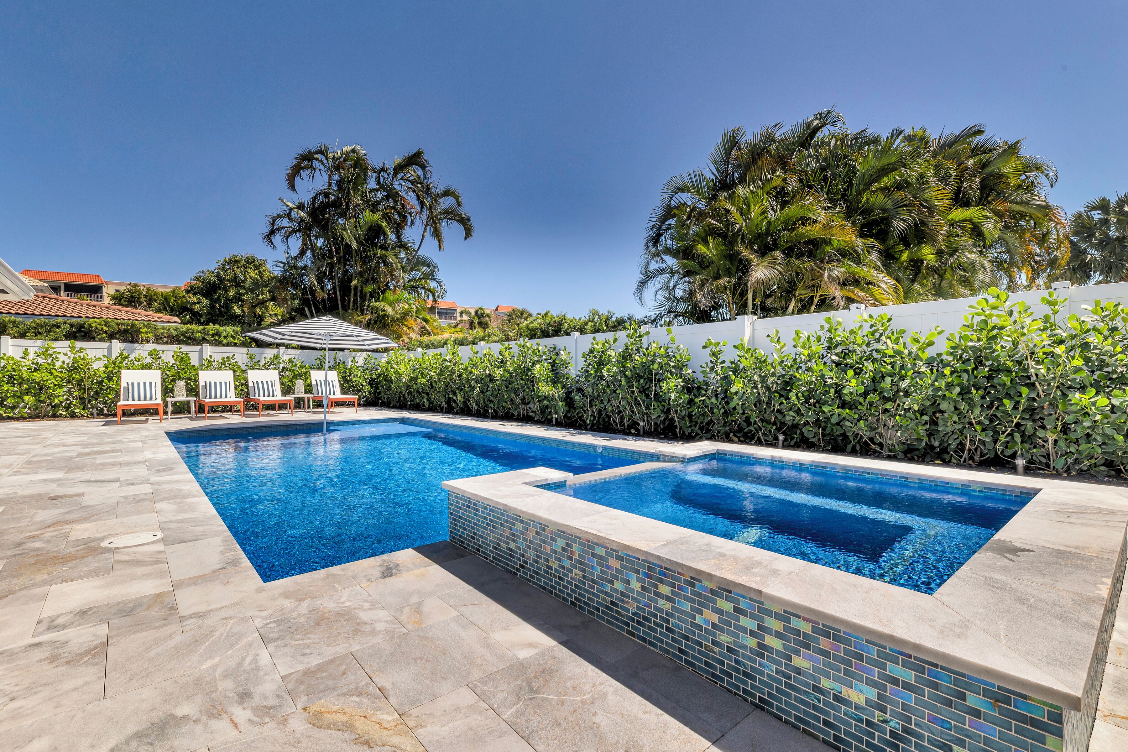 A rectangular swimming pool with a tiled edge, surrounded by a paved patio.