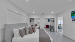 Un dormitorio moderno con una cama grande, un armario y un baño a la vista.